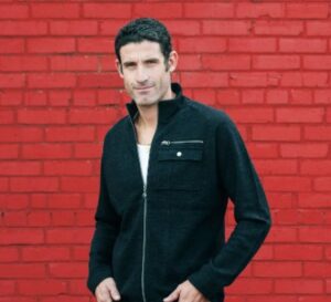 george hincapie stands in front of a red brick wall