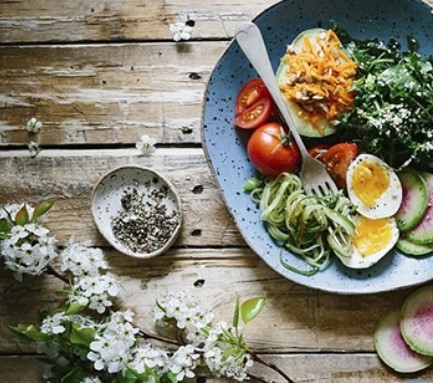 plate of salad and other vegetables on a wooden table with flowers
