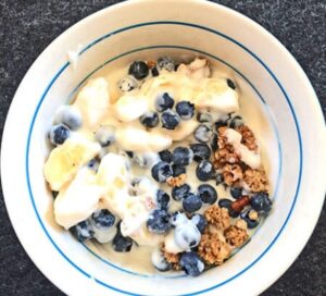 bowl of granola with blueberries bananas and yogurt