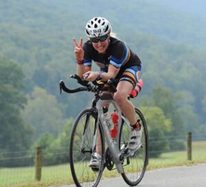 woman riding bike gives a peace sign with one hand