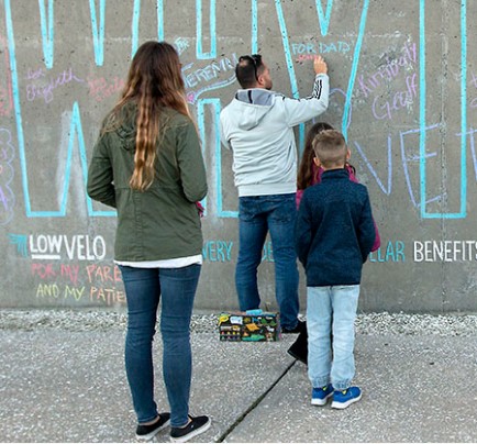 lowvelo participants write a message in chalk on the memory wall