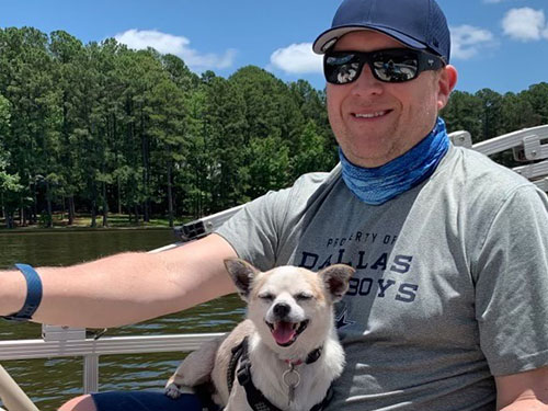 Doug McCracken sits in a boat with a dog on his lap