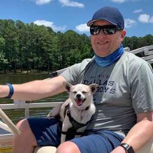 Doug McCracken sits in a boat with a dog on his lap
