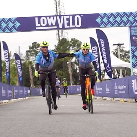 Two riders cross the finish line at Lowvelo19 with their hands on each other's shoulders