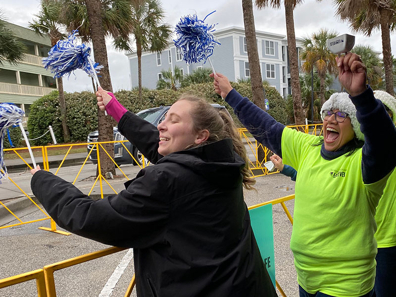 volunteers cheer riders and wave pom poms
