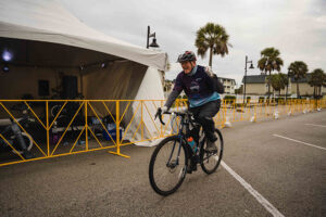 Dr. Raymond DuBois rides past tent and pumps his fist