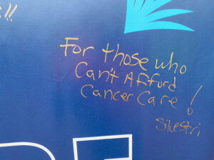 Close up of handwritten Why I Ride message that says For those who can't afford cancer care