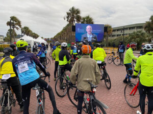 large group of riders watch welcome video on video board screen
