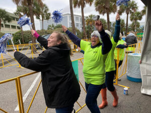 three volunteers cheer and wave pom poms