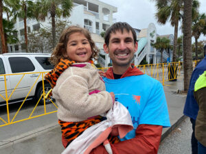 rider holds his daughter in his arms at finish line party