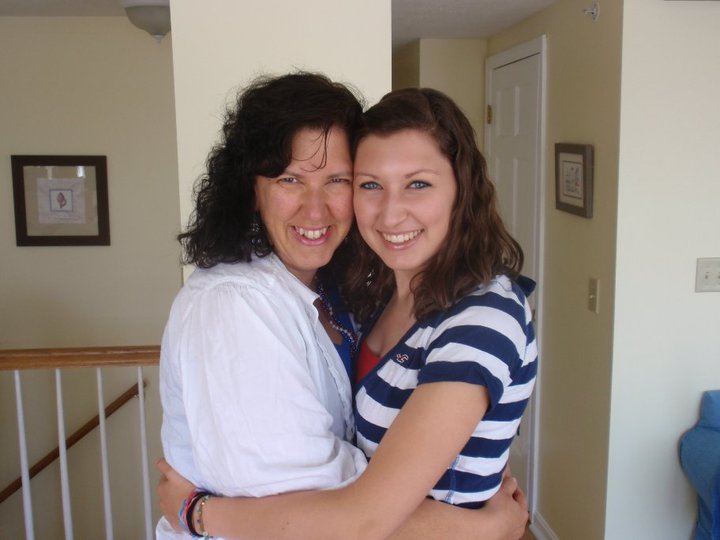 Teenage girl hugging her mother and smiling at the camera