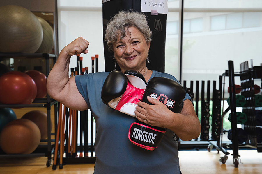 a woman holding boxing gloves in a gym flexes her arm