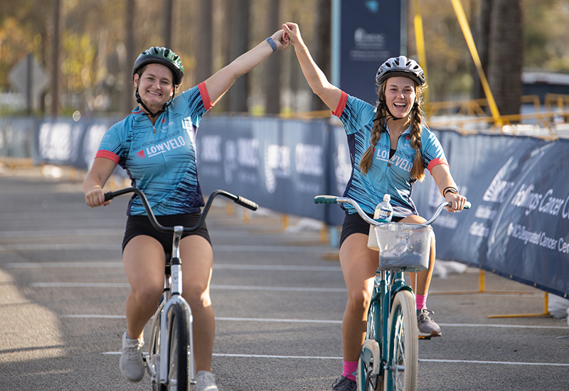 two riders hold hands in celebration as they cross the finish line