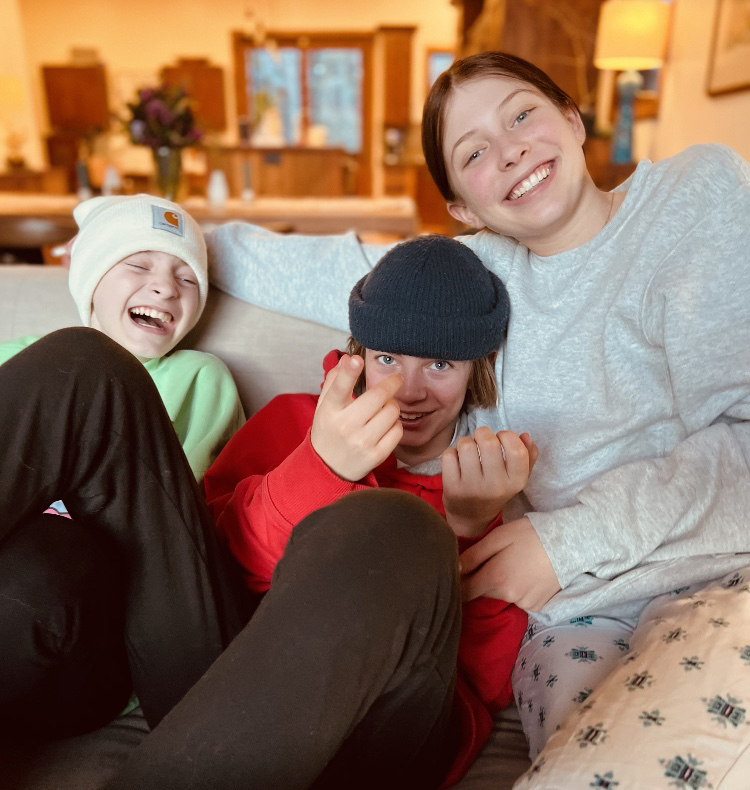 three kids laughing and cuddling on couch