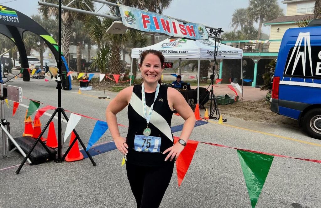 Jennifer Dahne poses at the finish line after completing a half marathon