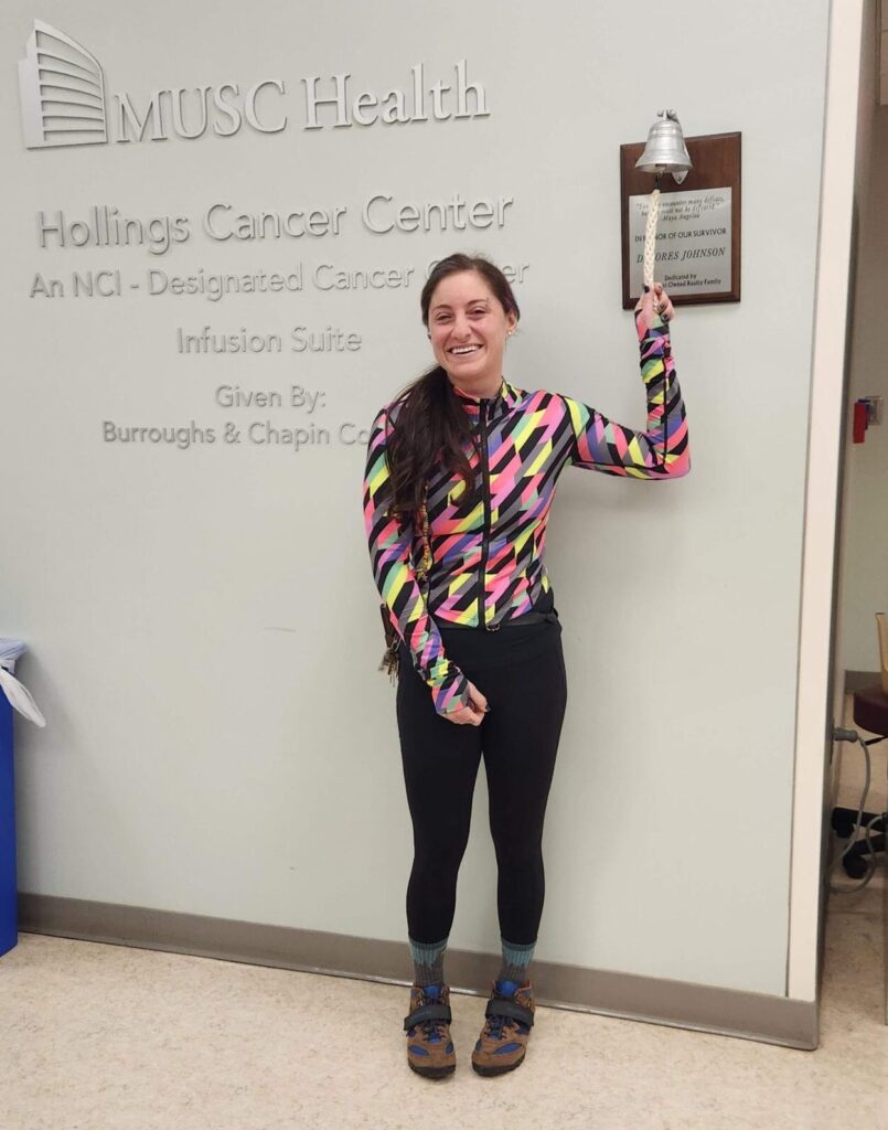 Womanin cycling gear ringing the bell at Hollings Cancer Center