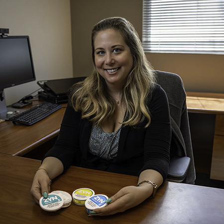 Woman sitting at a desk with oral nicotine pouches on the desk in front of her