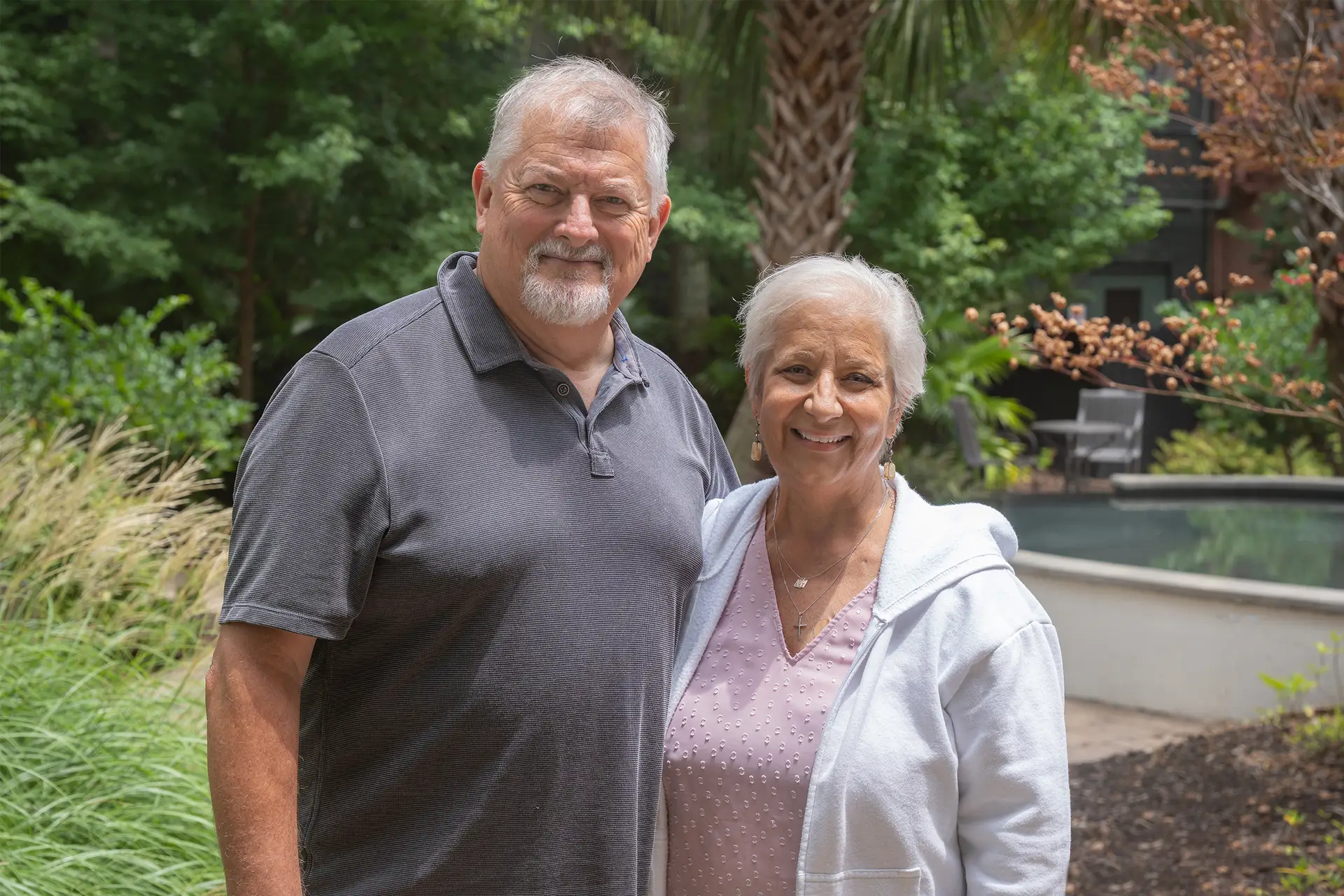 A couple stands together in a garden setting