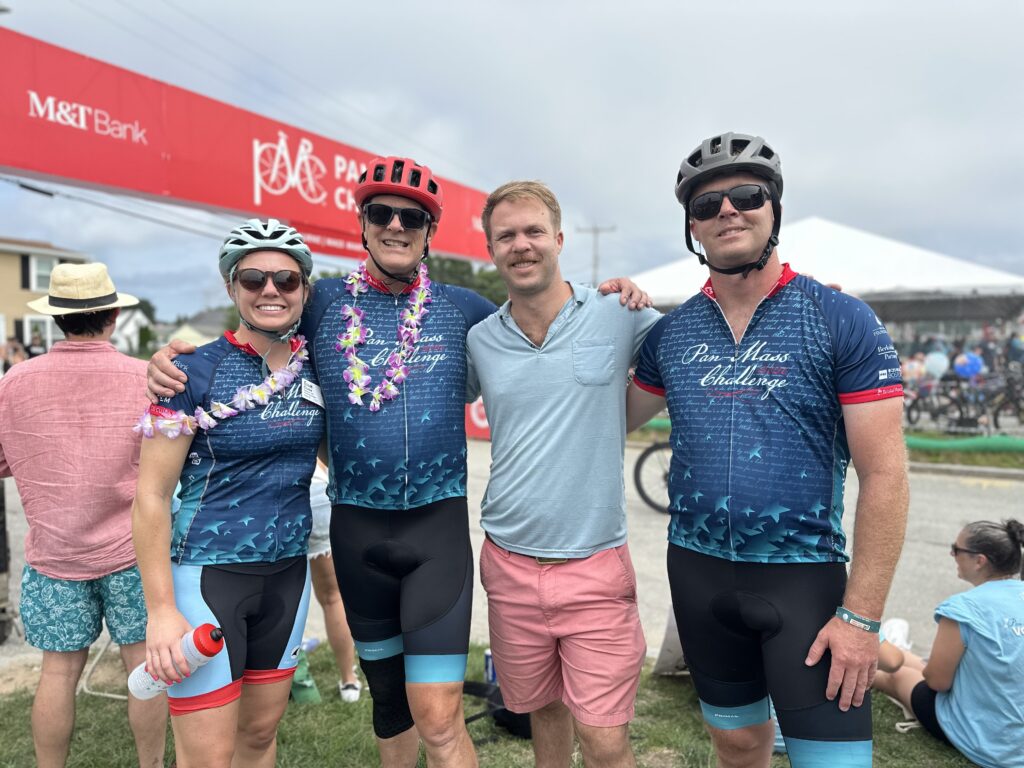 A group of cyclists in matching outfits smile for the camera