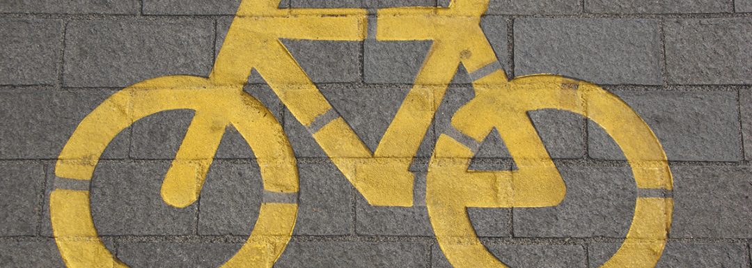 yellow bike icon painted onto a sidewalk