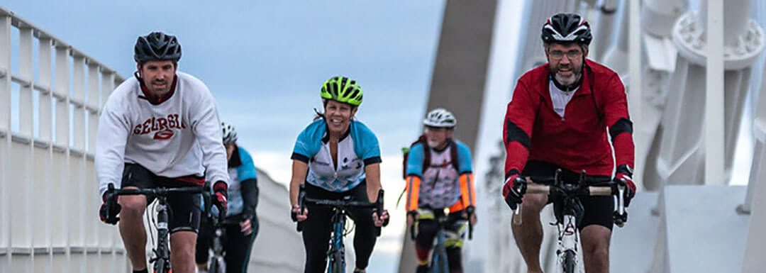 group of cyclists riding over the ravenel bridge